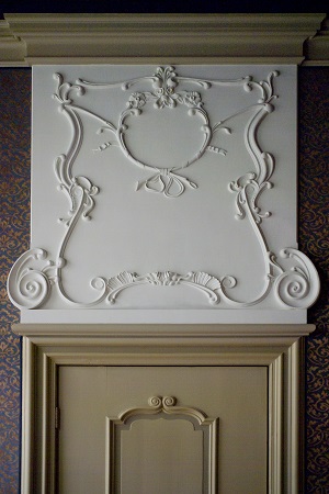 Decoratief stucwerk boven deur en schouw met klassiek ornament